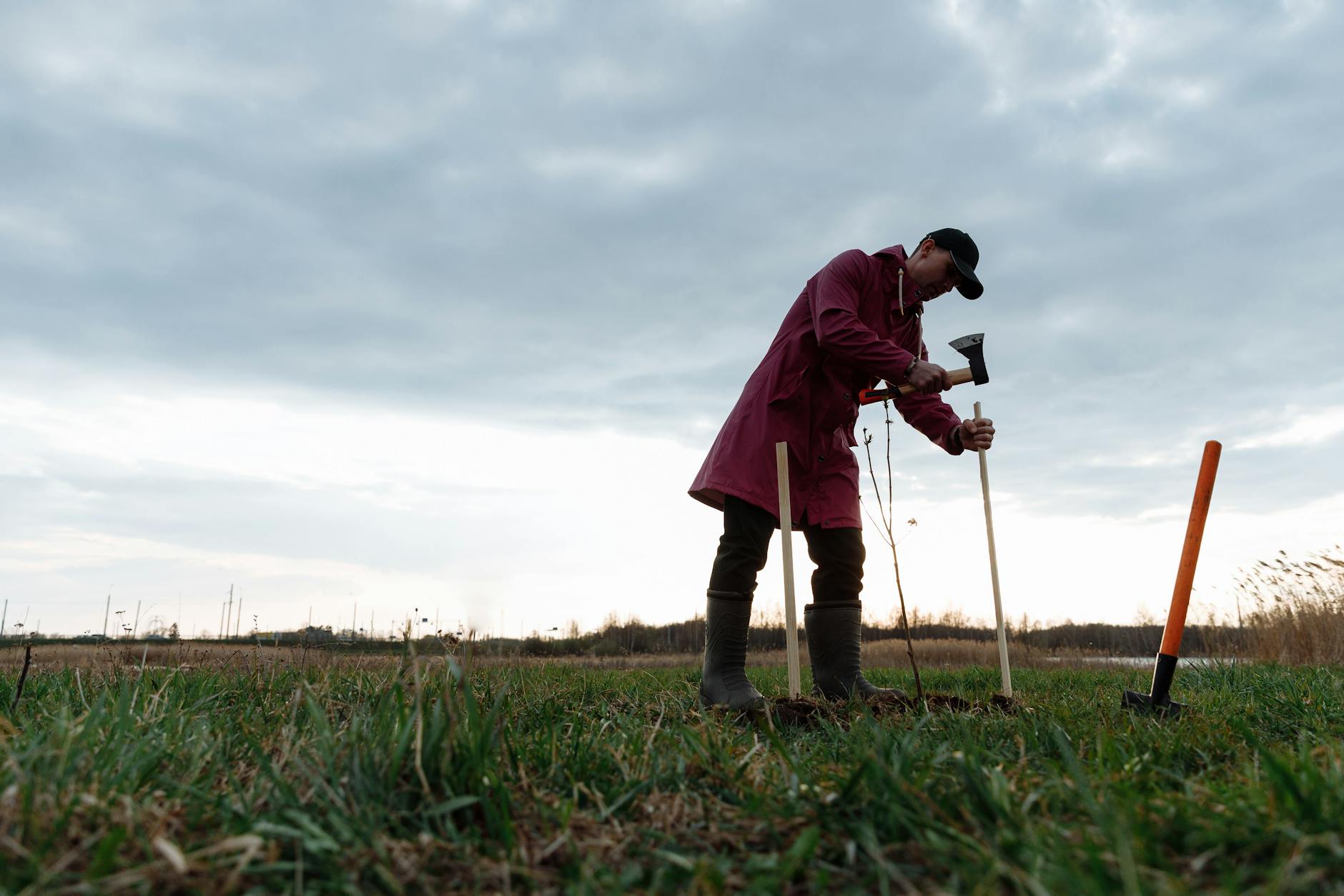 man in red jacket and black pants holding black dslr camera on green grass field during